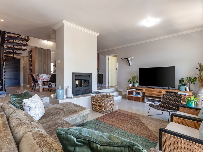 Spacious open-plan living area featuring a central built-in fireplace, elegant spiral staircase, and bright, tiled flooring throughout.