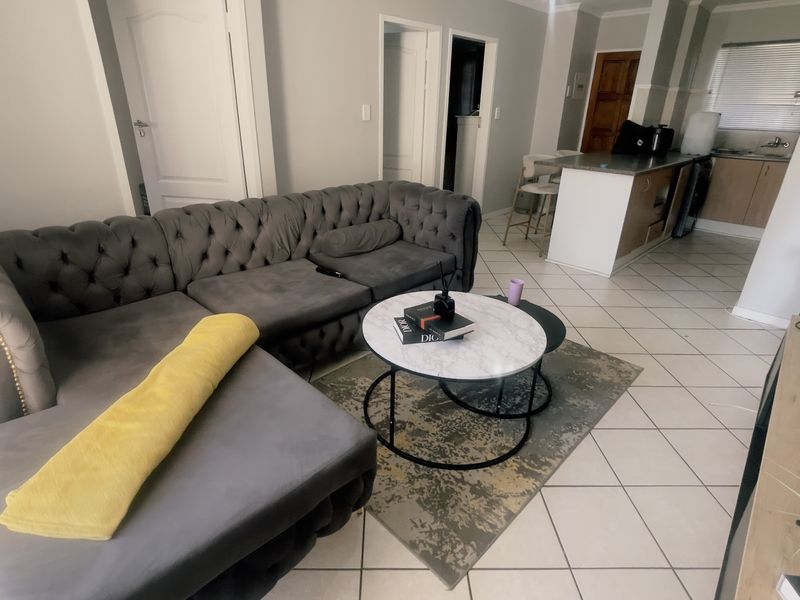 Open-plan living area featuring tiled flooring and a functional kitchen with a central island, creating a connected space for living and dining.