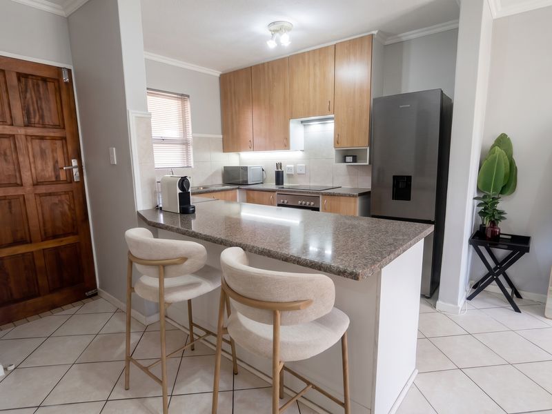 A functional kitchen featuring granite countertops, built-in cabinetry, an electric hob, and a breakfast nook, finished with tiled flooring.