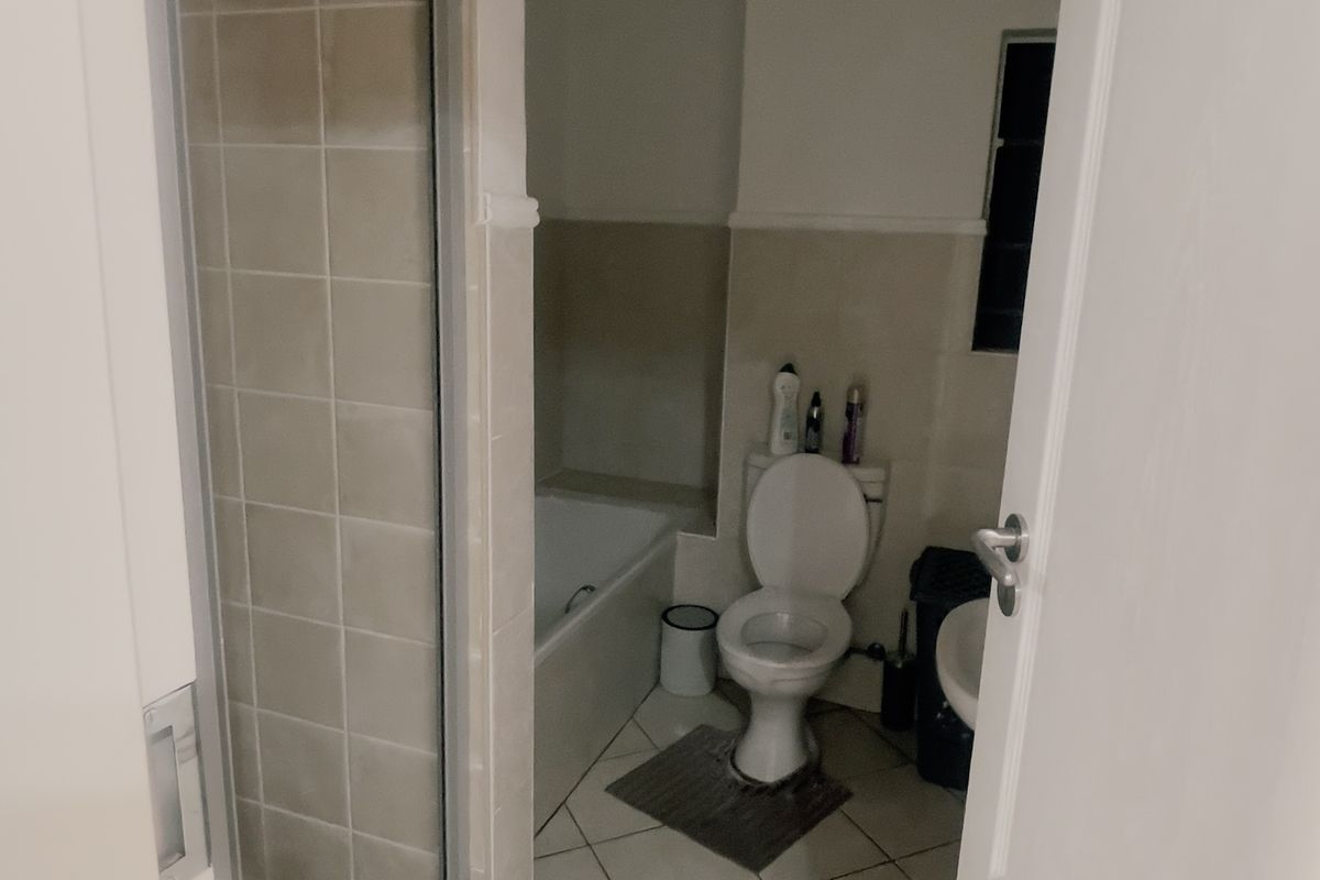 A functional bathroom featuring a separate shower enclosure, bathtub, toilet, and washbasin with neutral wall and floor tiling.