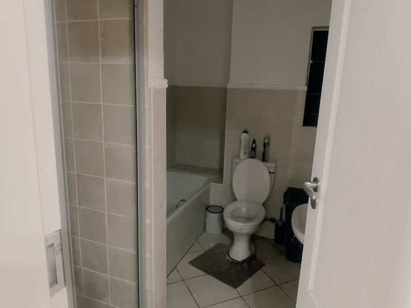 A functional bathroom featuring a separate shower enclosure, bathtub, toilet, and washbasin with neutral wall and floor tiling.