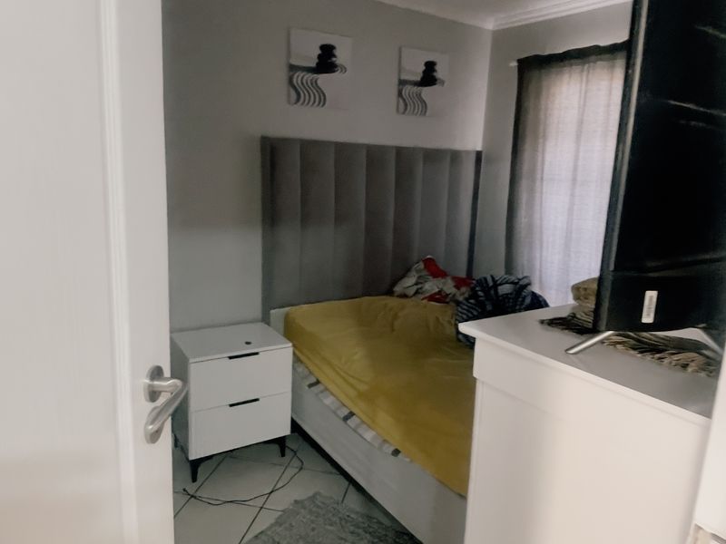 A compact bedroom featuring tiled flooring, a neutral wall finish, and a built-in headboard, offering a functional space for rest.