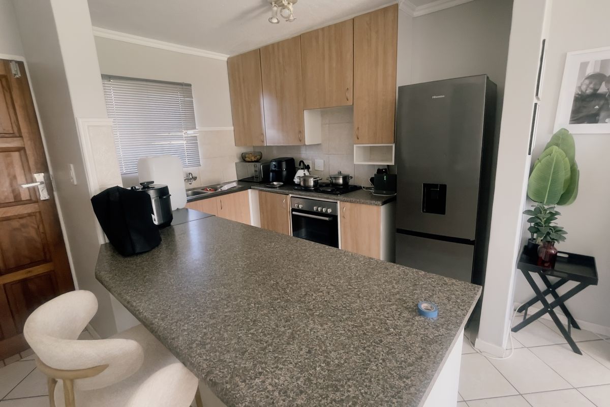 A functional kitchen featuring laminate cabinetry, granite countertops, a built-in oven, and a breakfast bar, finished with tiled flooring.