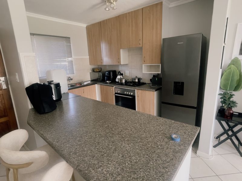 A functional kitchen featuring laminate cabinetry, granite countertops, a built-in oven, and a breakfast bar, finished with tiled flooring.