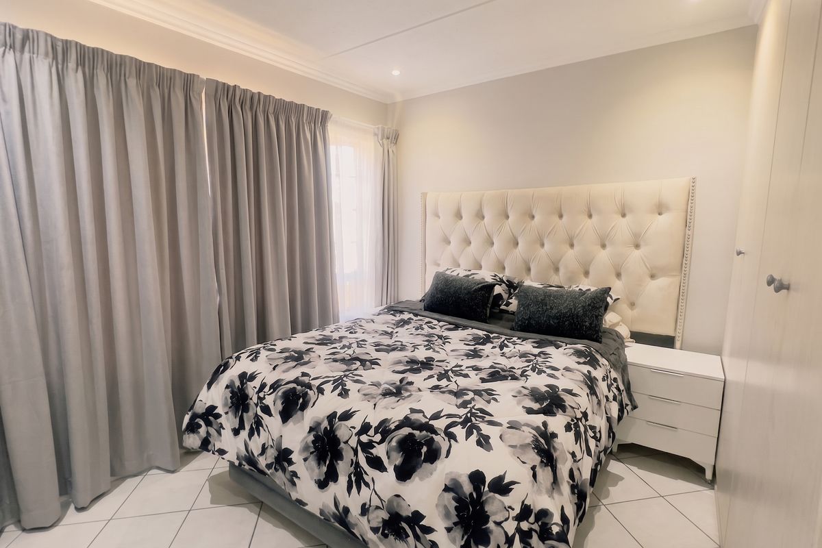 A well-maintained bedroom featuring tiled flooring, built-in cupboards, and decorative cornicing, providing a clean and functional living space.