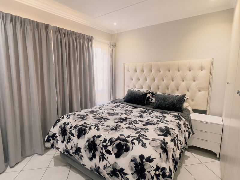 A well-maintained bedroom featuring tiled flooring, built-in cupboards, and decorative cornicing, providing a clean and functional living space.