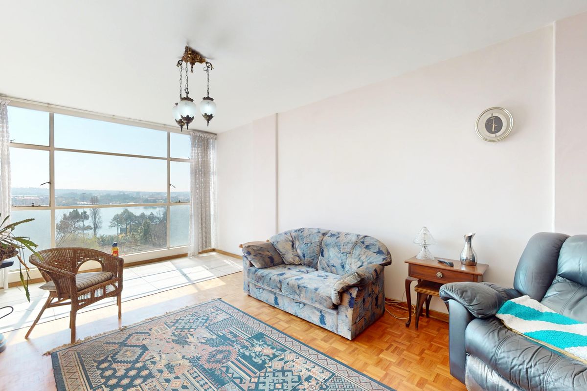 Spacious living room featuring classic parquet flooring and expansive floor-to-ceiling windows that offer abundant natural light and scenic views.