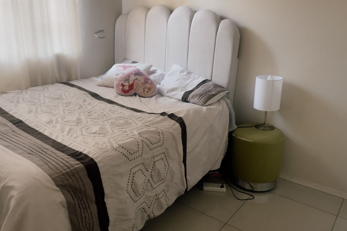 A bedroom featuring neutral wall finishes and tiled flooring, providing a functional and comfortable sleeping space.