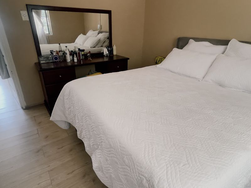 A bedroom featuring light-toned laminate flooring and neutral wall paint, providing a functional and comfortable sleeping space.