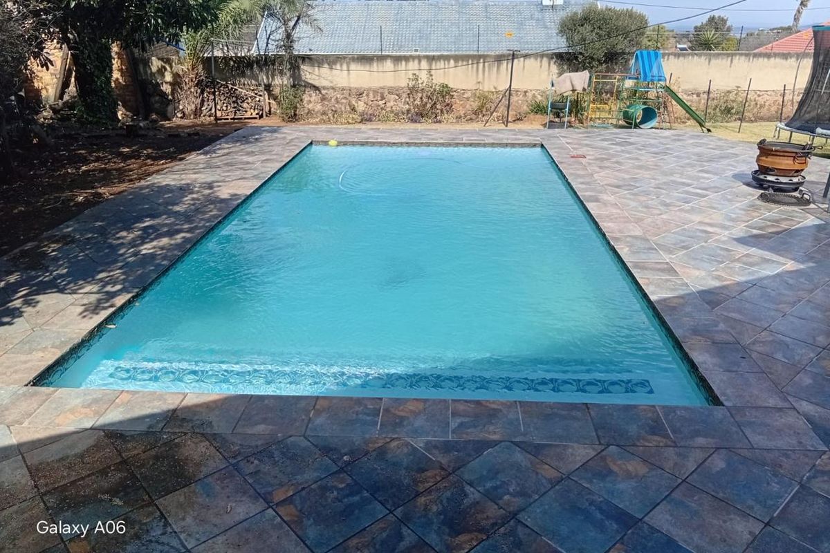 A rectangular swimming pool featuring a tiled surround and perimeter boundary wall, set within a private backyard area.