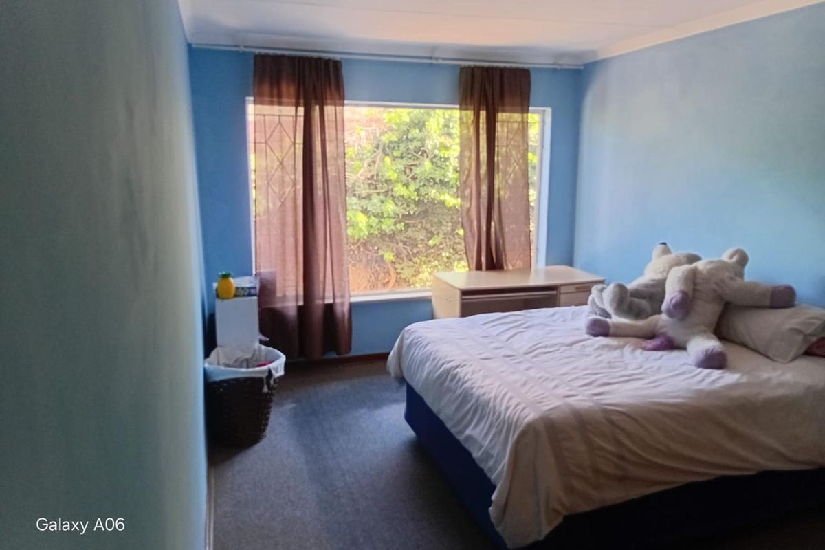 A standard bedroom featuring carpeted flooring, a large window providing natural light, and coved ceiling detailing.