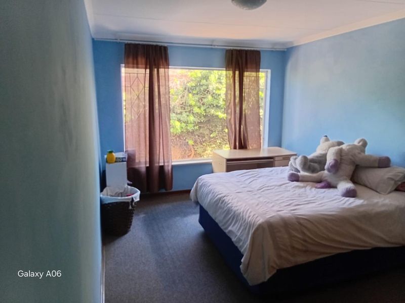 A standard bedroom featuring carpeted flooring, a large window providing natural light, and coved ceiling detailing.