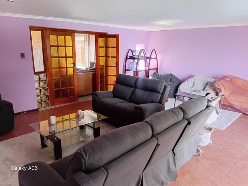 Spacious living room featuring tiled flooring, coved ceilings, and timber-framed French doors leading to an adjacent area.