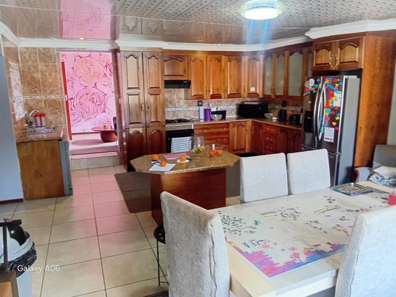 Open plan kitchen and dining area featuring traditional wooden cabinetry, granite countertops, and tiled flooring with a drop ceiling.