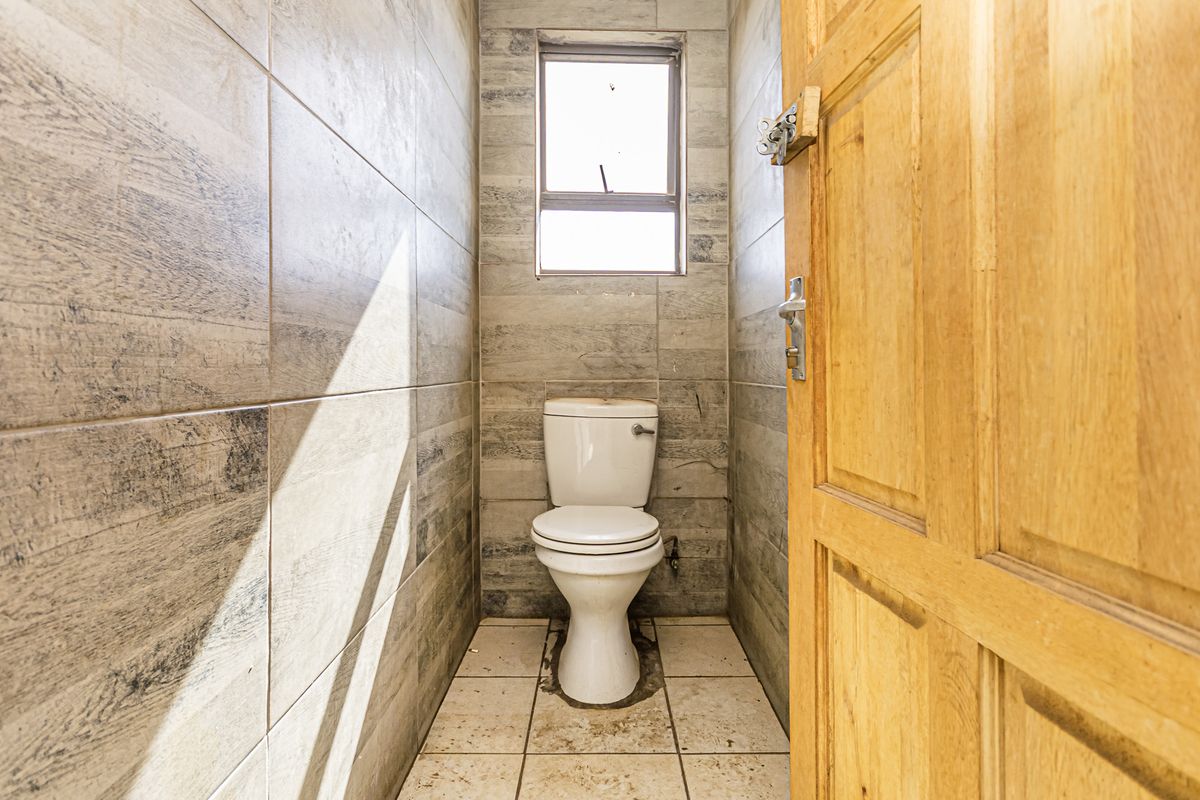 A compact bathroom featuring floor-to-ceiling wood-look wall tiles, tiled flooring, and a standard toilet fixture.