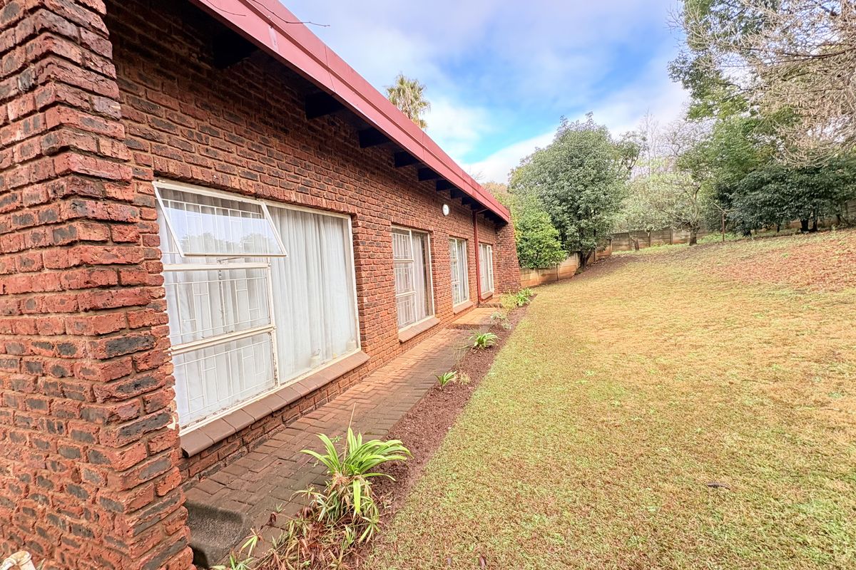 Rear view of the property featuring a face brick facade, metal window frames with security bars, and a paved walkway leading to the garden.