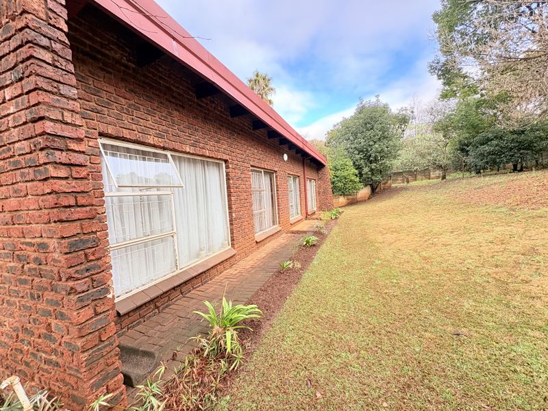 Rear view of the property featuring a face brick facade, metal window frames with security bars, and a paved walkway leading to the garden.