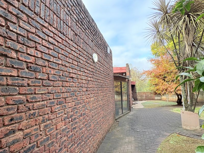 A view of the rear exterior featuring a face brick wall, paved pathway, and access to the home via a sliding glass door.