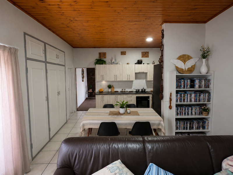 Open-plan kitchen and dining area featuring tiled floors, timber ceiling, and ample built-in cabinetry, creating a functional and connected living space.