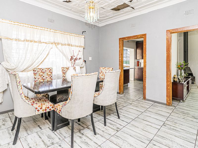 Dining room featuring tiled flooring and decorative ceiling tiles, with access to adjacent living and kitchen areas through timber-framed doorways.