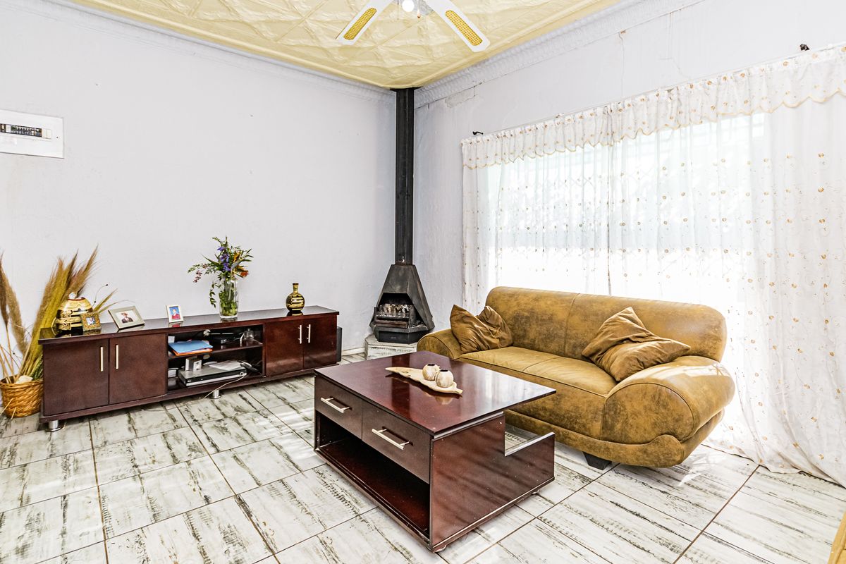 Living room featuring a freestanding fireplace, tiled flooring, and a textured ceiling with a central fan.