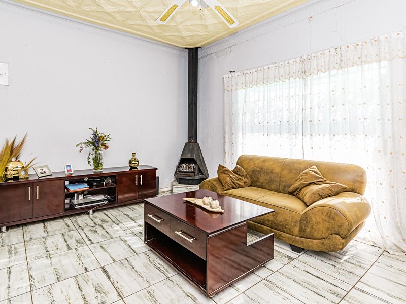 Living room featuring a freestanding fireplace, tiled flooring, and a textured ceiling with a central fan.
