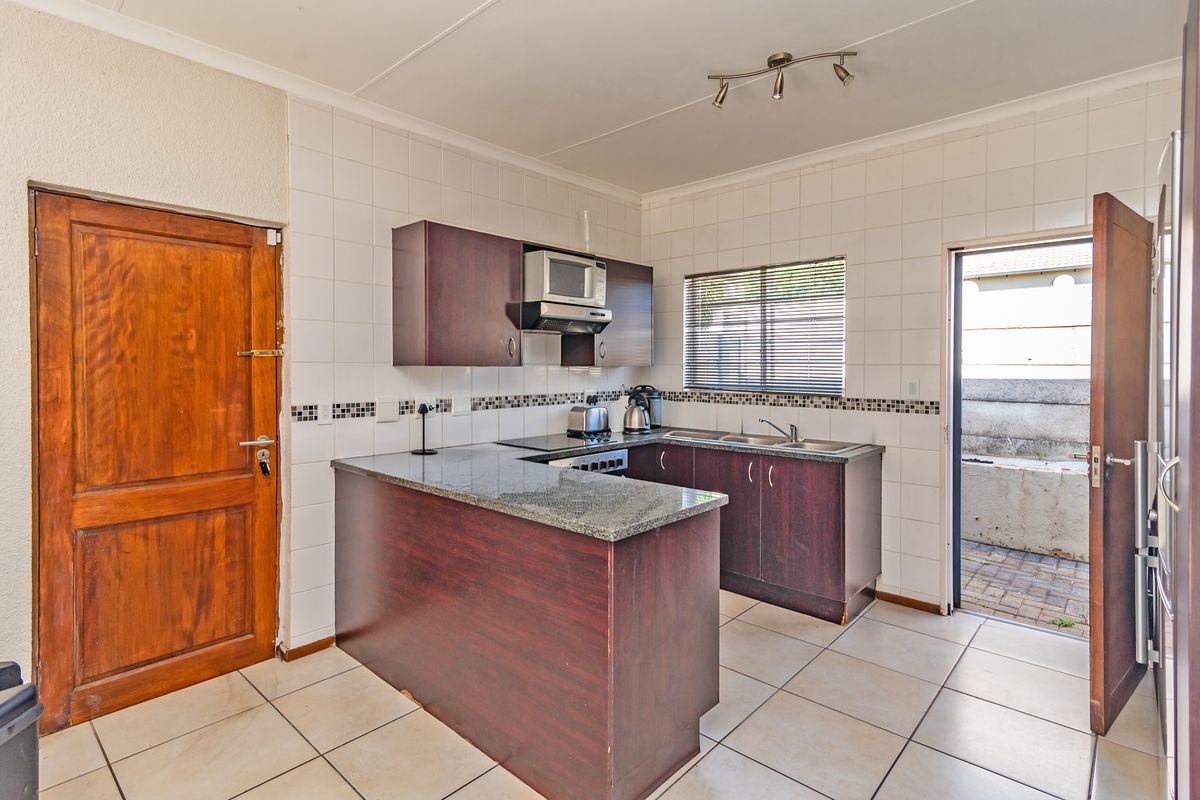 Functional kitchen featuring dark wood cabinetry, granite countertops, tiled backsplash, and direct access to an outdoor area.