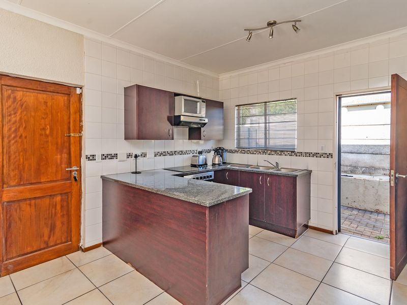 Functional kitchen featuring dark wood cabinetry, granite countertops, tiled backsplash, and direct access to an outdoor area.