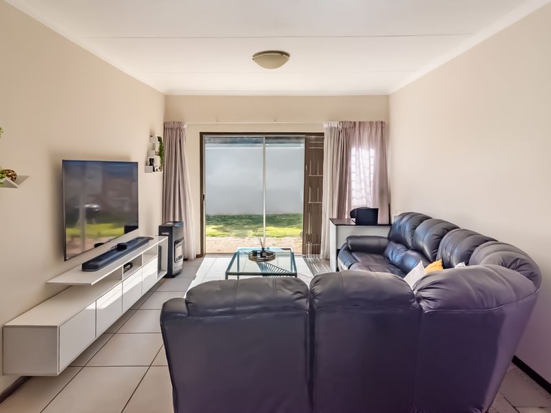 A bright living room featuring tiled flooring and a sliding glass door providing direct access to the rear patio and garden area.