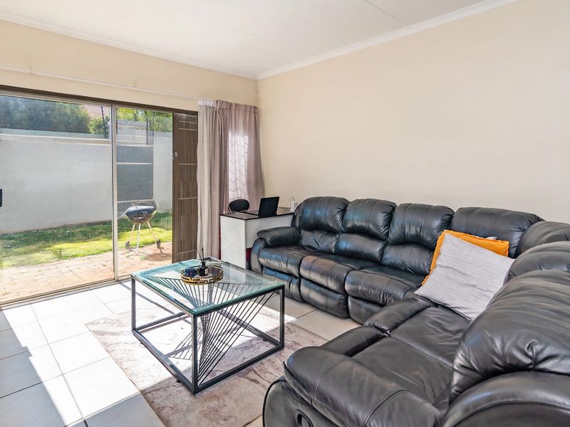 A bright living room featuring tiled flooring and a large sliding glass door providing direct access to the rear garden area.