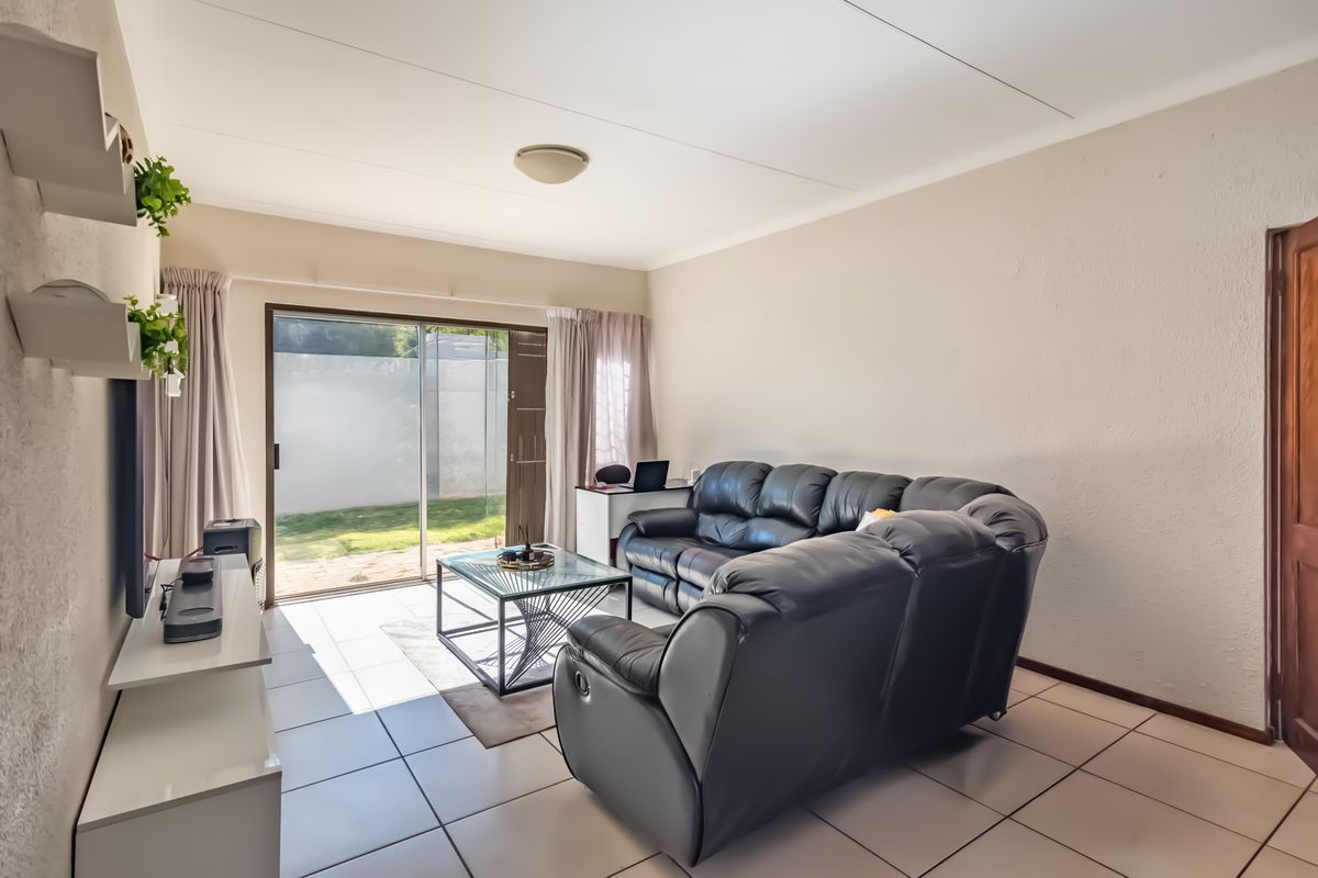A bright living room featuring tiled flooring and a sliding glass door providing direct access to the rear garden area.