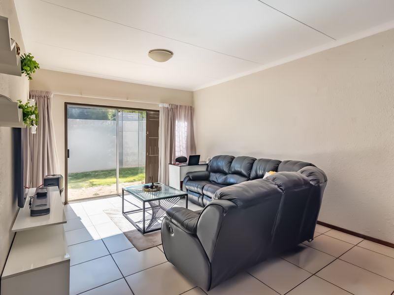 A bright living room featuring tiled flooring and a sliding glass door providing direct access to the rear garden area.