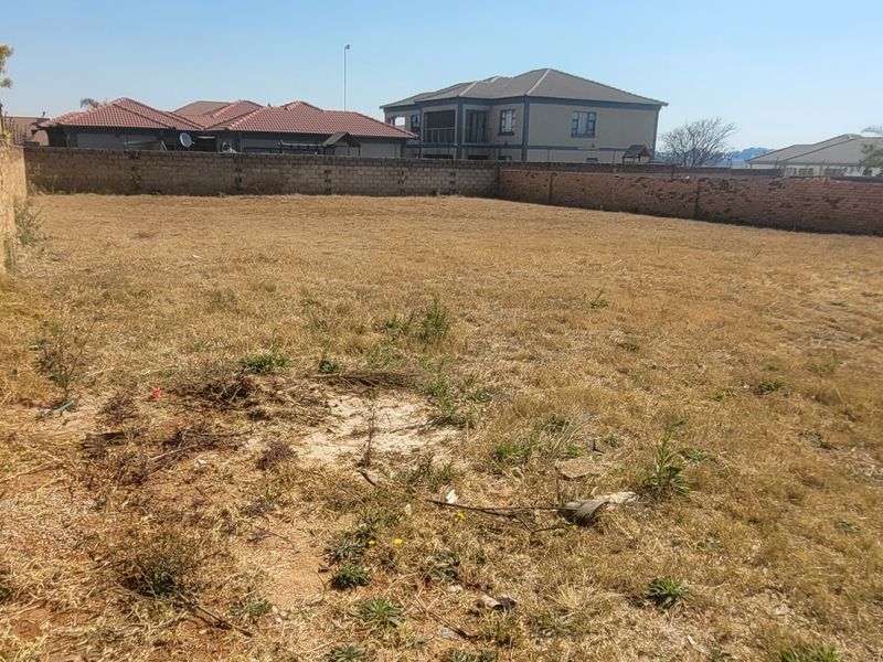 A vacant residential plot enclosed by perimeter brick walls, offering a clear space ready for development in a suburban neighborhood.