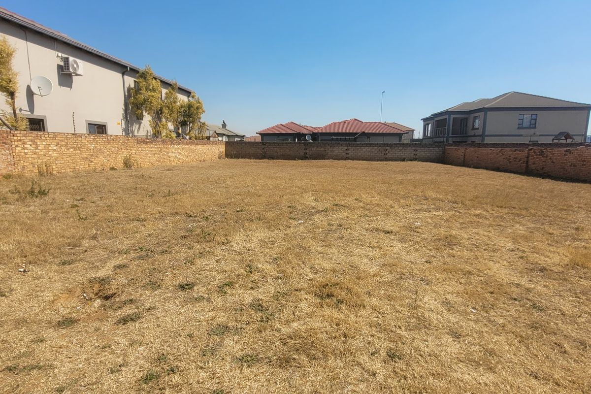 A vacant residential plot of land enclosed by brick boundary walls, offering a clear space for future development.