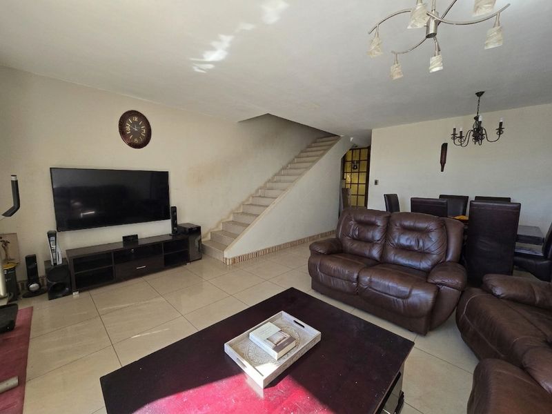 Spacious open-plan living and dining area featuring tiled flooring and a central staircase, offering a functional layout for family living.