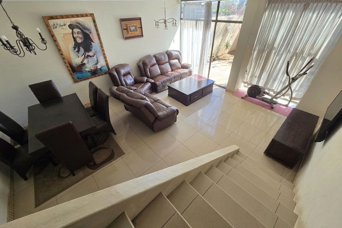 Spacious open-plan living and dining area featuring tiled flooring, a staircase, and large sliding glass doors providing access to the outdoor patio.