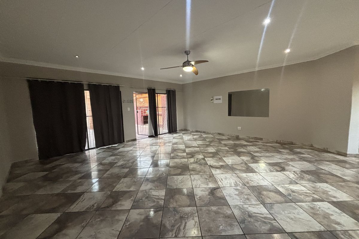 Spacious, empty living area featuring large format tiled flooring, recessed lighting, a ceiling fan, and sliding glass doors leading to an outdoor space.