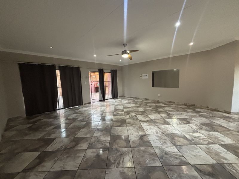 Spacious, empty living area featuring large format tiled flooring, recessed lighting, a ceiling fan, and sliding glass doors leading to an outdoor space.