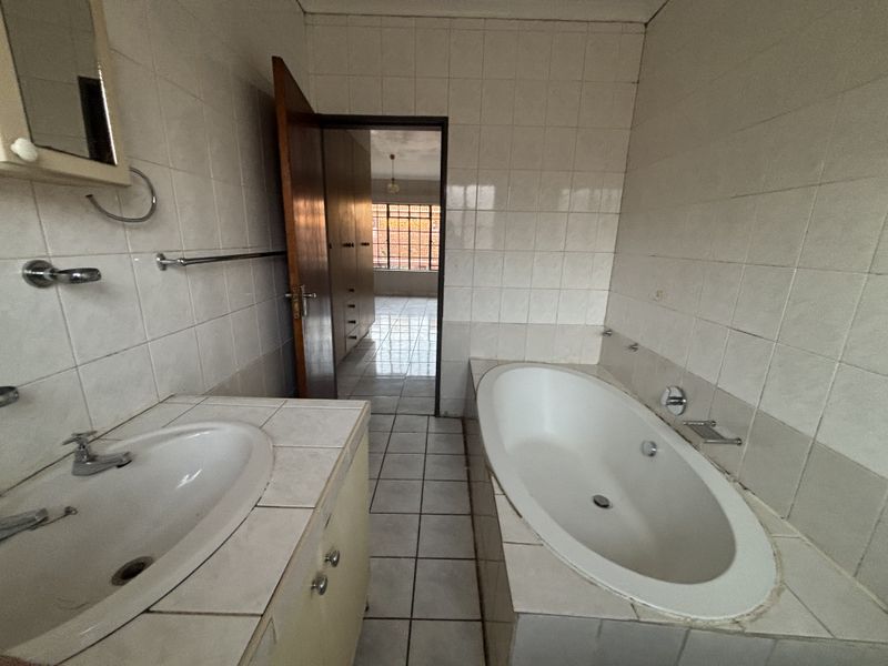 A dated bathroom featuring a built-in vanity with basin and a tiled drop-in bathtub, requiring cosmetic updates to modernize the space.
