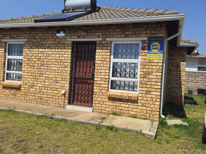 Front elevation of a face brick house featuring a tiled roof, solar water heater, and secure window and door fittings.