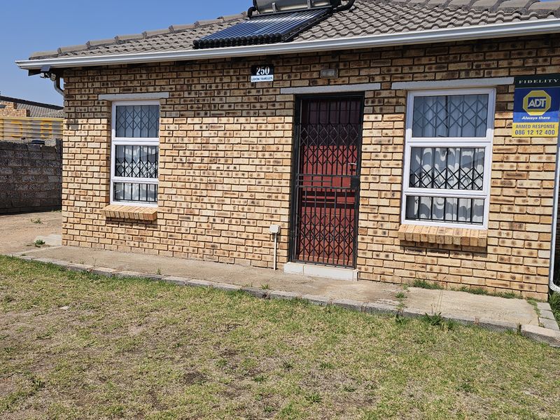 Front elevation of a face brick house featuring a solar water heater, security gate, and security bars on windows.