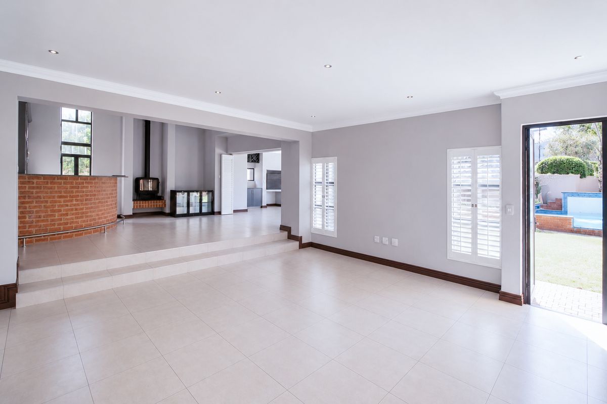 Spacious open-plan living area featuring a raised platform, brick fireplace with wood-burning stove, tiled flooring, and direct access to the garden.