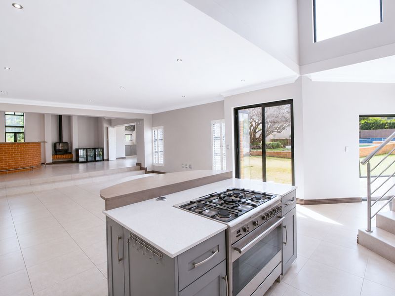 Spacious open-plan living area featuring a modern kitchen island with gas cooktop, tiled floors, fireplace, and direct access to the garden.