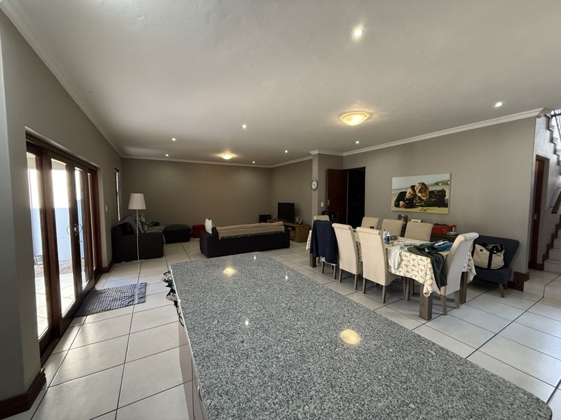 Spacious open-plan living and dining area featuring a large granite kitchen island, tiled flooring, and sliding glass doors leading to the exterior.