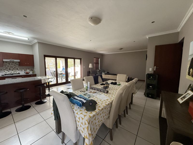Spacious open-plan living and dining area featuring a modern kitchen with granite countertops, tiled floors, and large sliding doors leading to the patio.