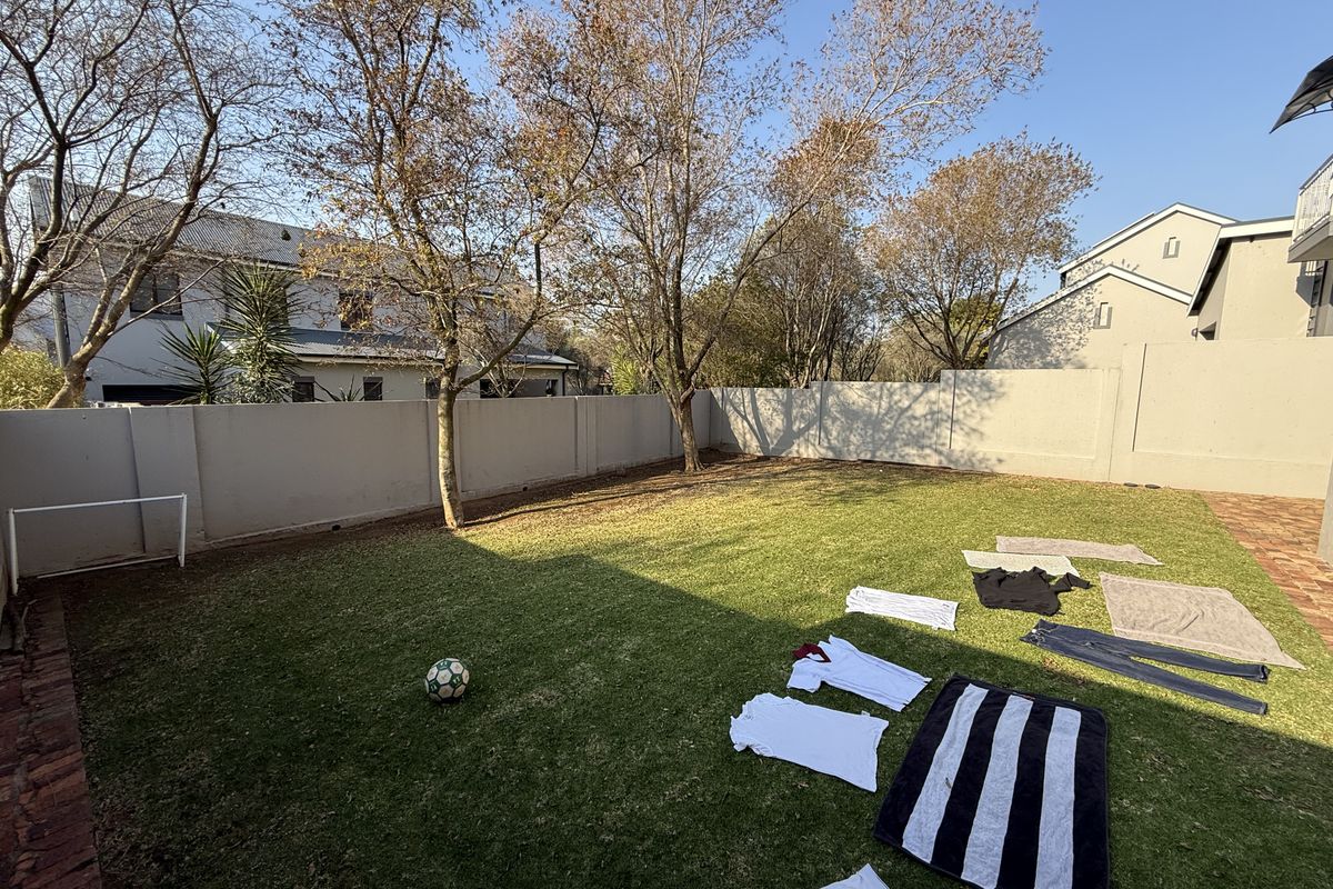 A private rear garden featuring a well-maintained lawn, perimeter boundary walls, and paved edging, providing a secure outdoor space.