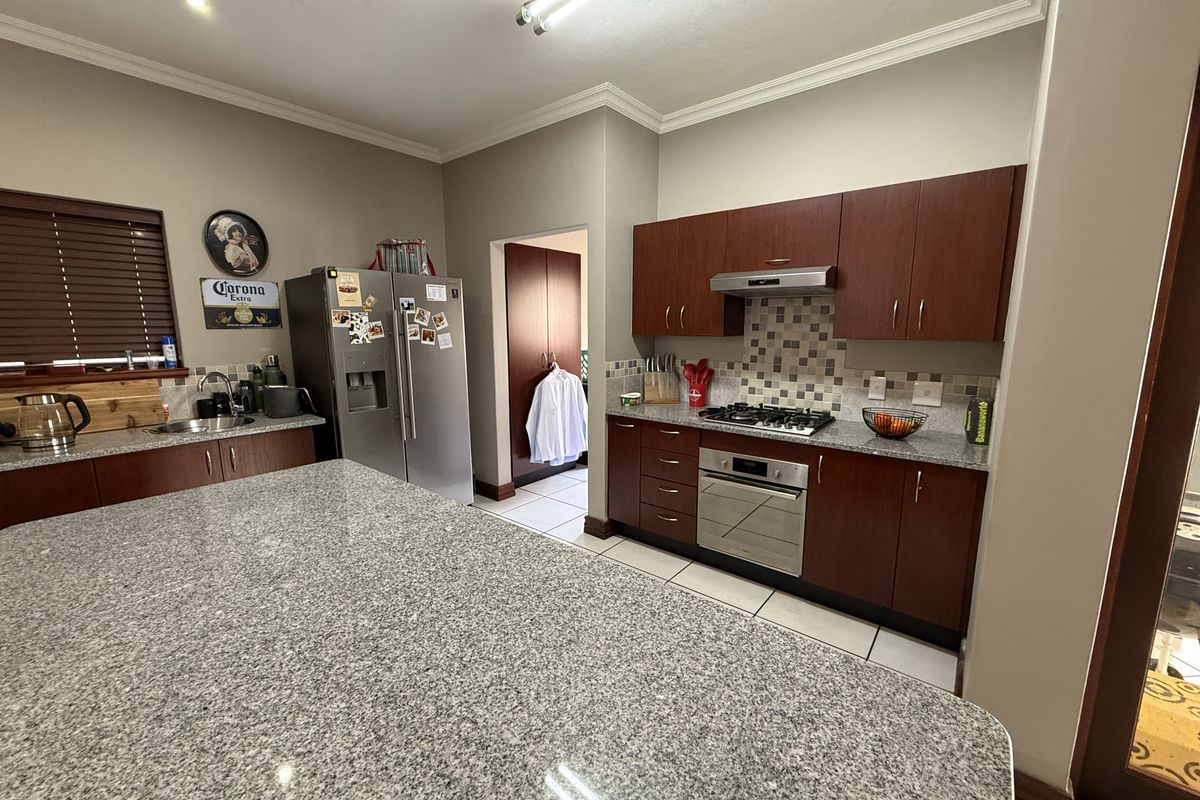 A functional kitchen featuring granite countertops, dark wood cabinetry, a built-in oven with gas hob, and a mosaic tile backsplash.