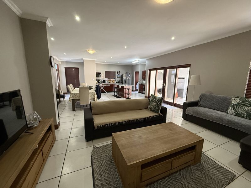 Spacious open-plan living and dining area featuring tiled floors, recessed lighting, and direct access to an outdoor patio through sliding glass doors.