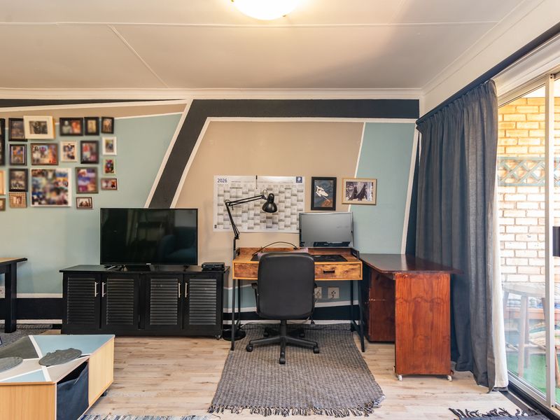 A living room area featuring laminate flooring and a large sliding glass door providing access to an outdoor space.
