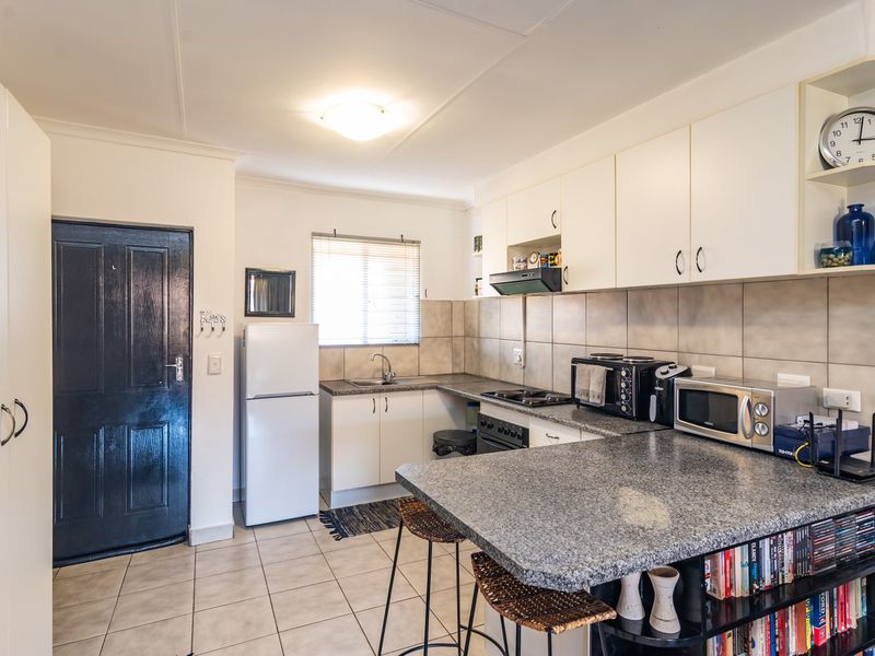A functional kitchen featuring granite countertops, ample built-in cabinetry, a breakfast bar, and tiled flooring, providing a practical workspace for daily cooking.